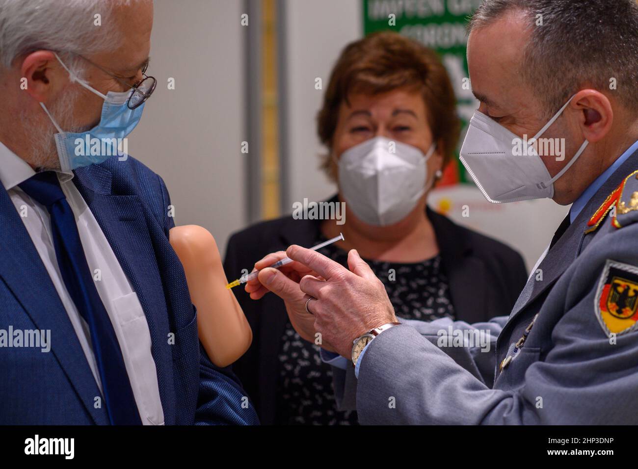 Magdeburg, Germania. 18th Feb 2022. 18 febbraio 2022, Sassonia-Anhalt, Magdeburg: Carsten Breuer (r), capo del personale della Cancelleria federale della Corona, prova la vaccinazione su un tampone di silicone indossato sul braccio superiore da Jens-Andreas Münch (l), presidente della Camera dei farmacisti Sassonia-Anhalt. Sullo sfondo è Petra Grimm-Benne (M, SPD), ministro del lavoro, degli affari sociali, della sanità e dell'uguaglianza della Sassonia-Anhalt. Tali cuscini sono utilizzati nelle sessioni di addestramento di vaccinazione. Prima di visitare la farmacia dove la vaccinazione inizierà nelle prossime settimane, il maggiore Generale dell'Arme tedesca Foto Stock