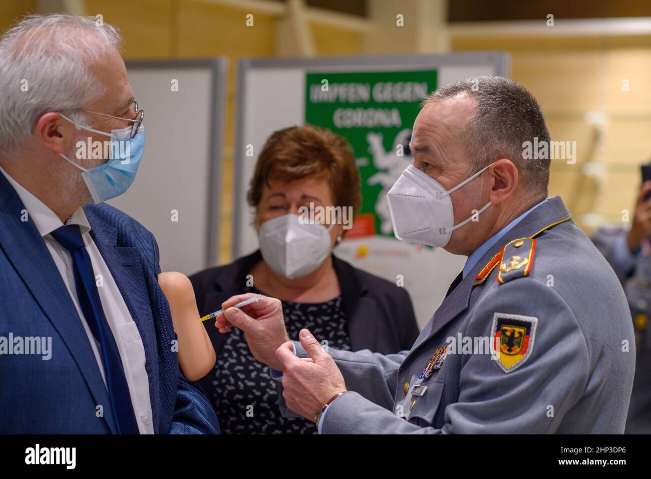 Magdeburg, Germania. 18th Feb 2022. 18 febbraio 2022, Sassonia-Anhalt, Magdeburg: Carsten Breuer (r), capo del personale della Cancelleria federale della Corona, prova la vaccinazione su un tampone di silicone indossato sul braccio superiore da Jens-Andreas Münch (l), presidente della Camera dei farmacisti Sassonia-Anhalt. Sullo sfondo è Petra Grimm-Benne (M, SPD), ministro del lavoro, degli affari sociali, della sanità e dell'uguaglianza della Sassonia-Anhalt. Tali cuscini sono utilizzati nelle sessioni di addestramento di vaccinazione. Prima di visitare la farmacia dove la vaccinazione inizierà nelle prossime settimane, il maggiore Generale dell'Arme tedesca Foto Stock