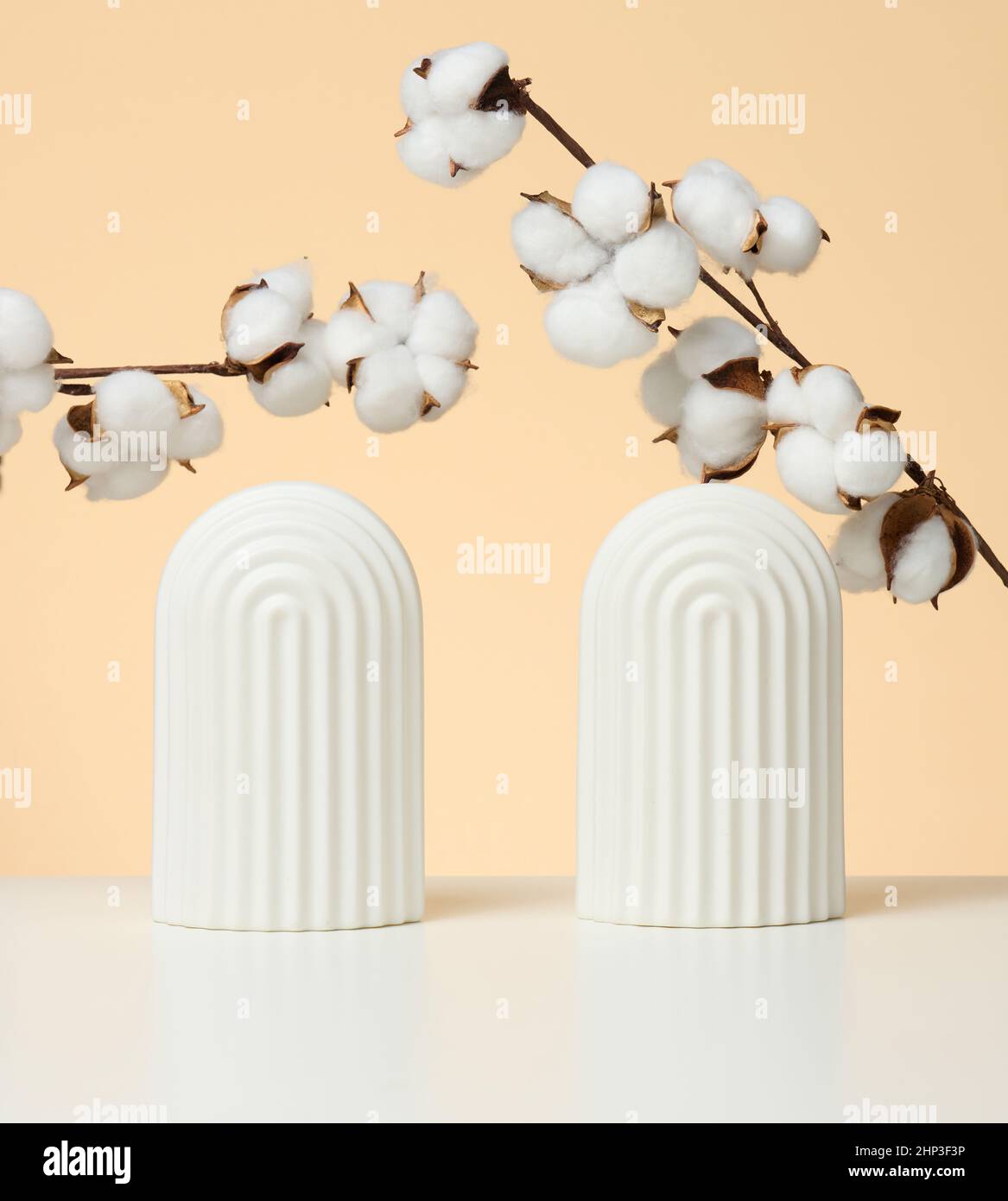 podio con cotone fiore bianco e archi per mostrare cosmetici, prodotti e altri prodotti, sfondo beige Foto Stock