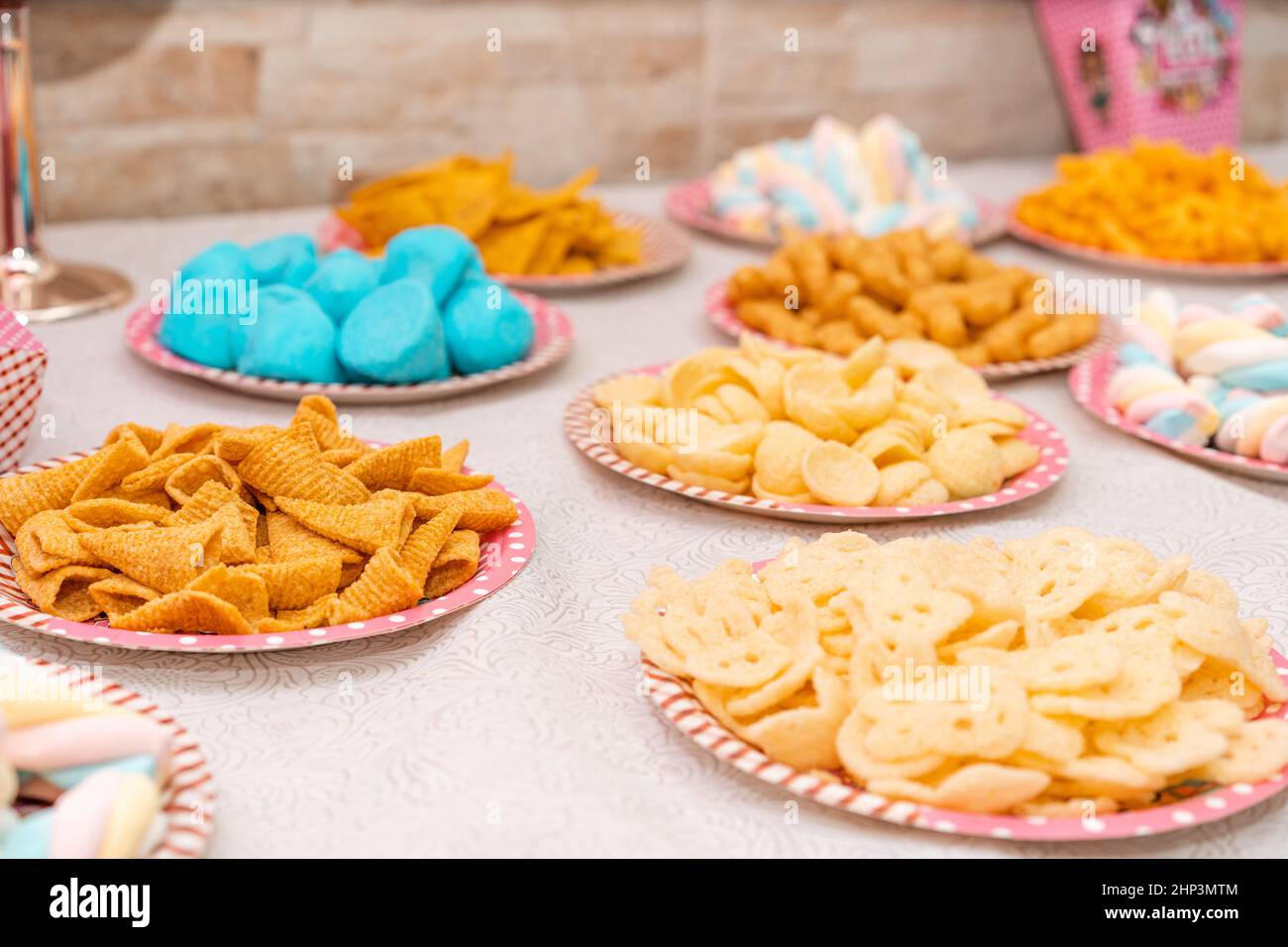 Tavolo con un sacco di cibi diversi per i bambini festa di compleanno. Focalizzazione selettiva sulle patatine di mais con cono dorato. Foto Stock