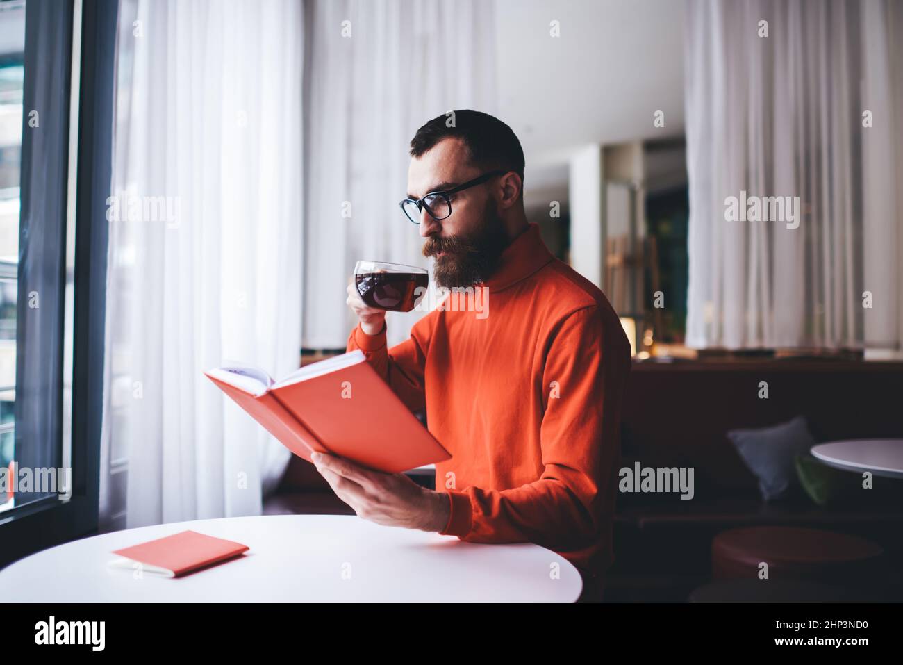 Uomo pensieroso leggere libro e bere tè Foto Stock