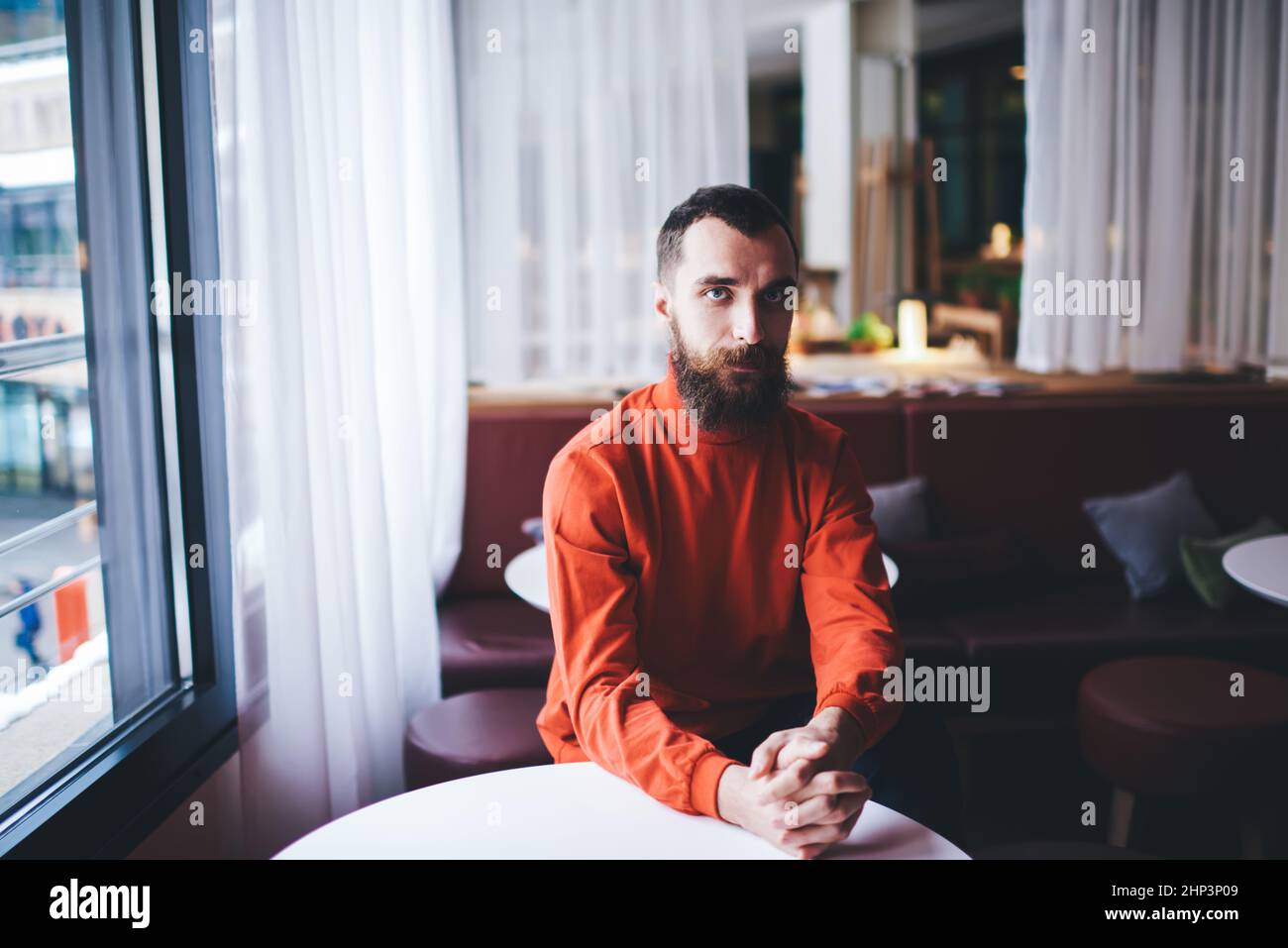 Uomo bearded con le mani piegate nella zona lounge Foto Stock