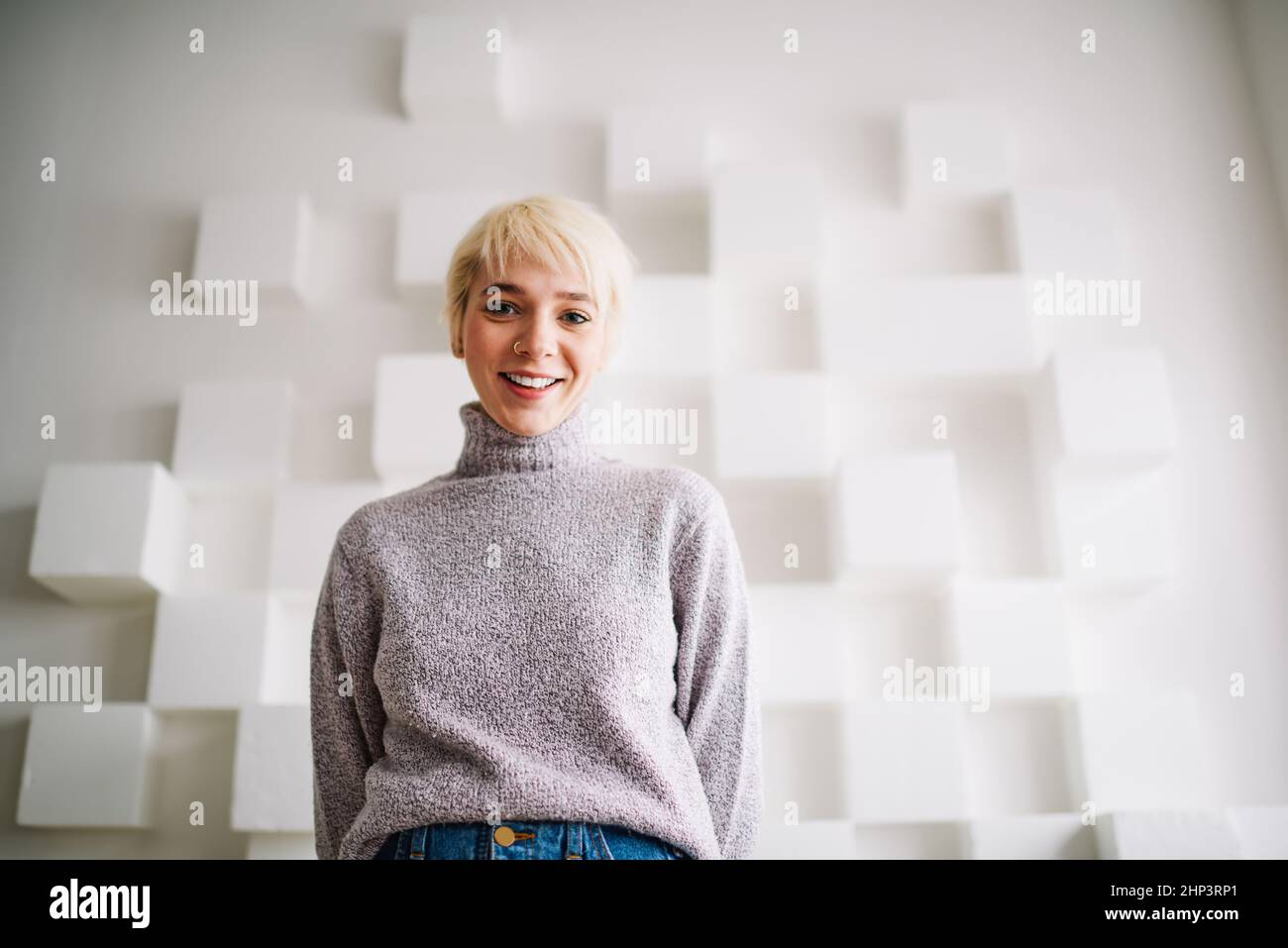 Donna felice vicino al muro con decorazioni cubiche Foto Stock