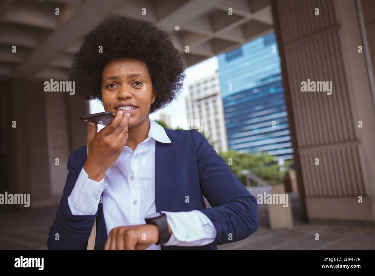 Donna d'affari afroamericana per adulti di media età che parla al telefono mentre si trova nei locali dell'edificio Foto Stock