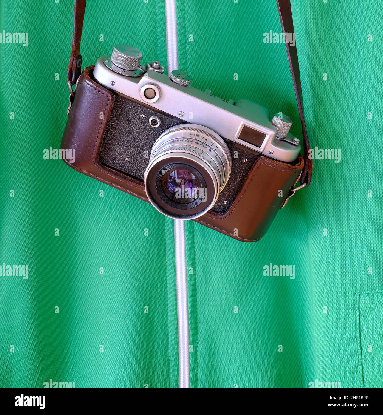 Fotocamera retrò appesa a una giacca verde con spazio per la copia Foto Stock