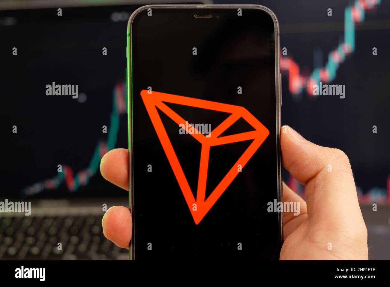 TRON TRX Cryptocurrency logo sullo schermo di uno smartphone in mano mans  con una tendenza crescente sul grafico su uno sfondo verde Foto stock -  Alamy
