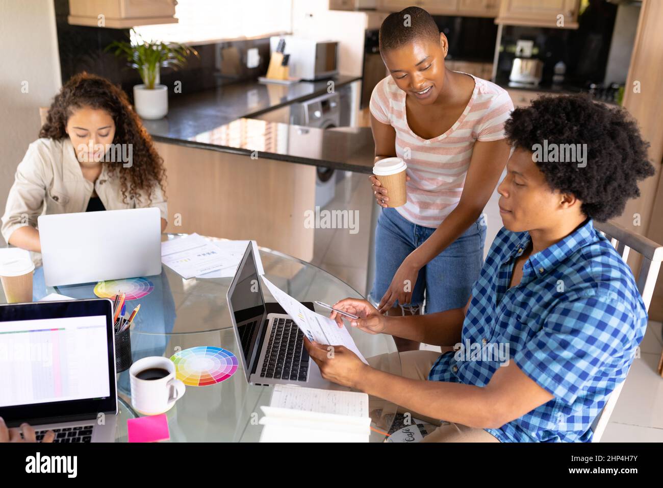 Colleghi aziendali multirazziali che discutono di documenti da parte di una donna d'affari che utilizza un notebook Foto Stock