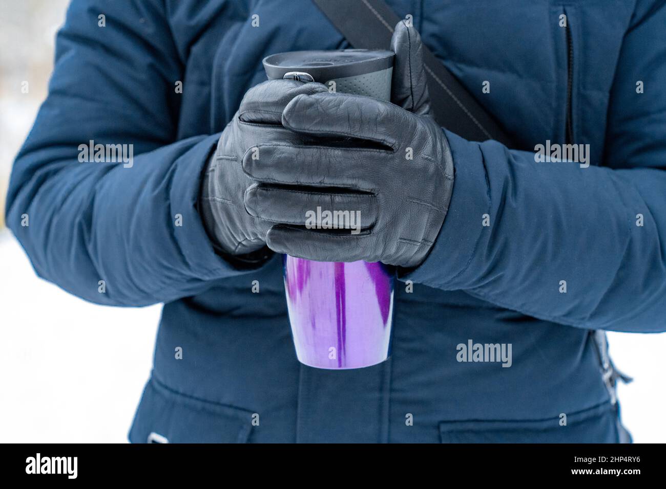 Primo piano delle mani di un uomo che tiene un thermos viola. Foto Stock