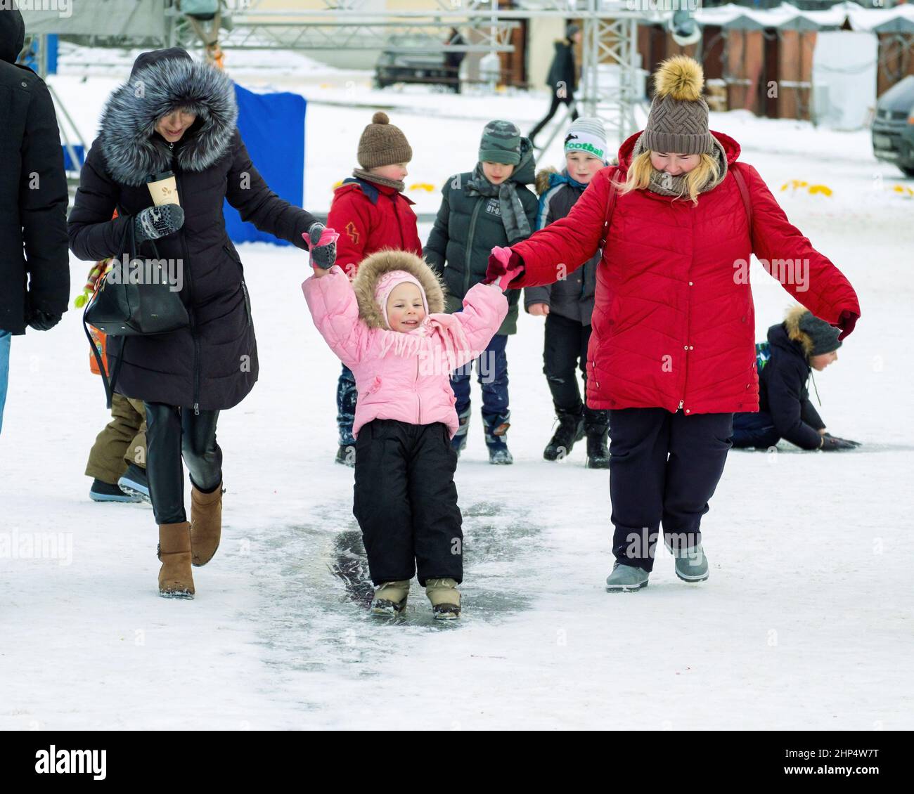 Divertimento invernale. I bambini si cavalcano sul ghiaccio in inverno. I genitori sono con loro. Foto Stock