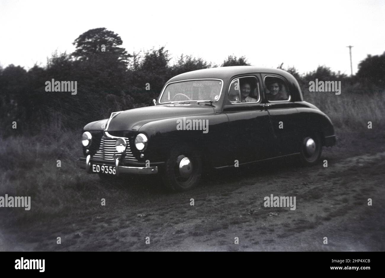 1940s, storico, fuori su una pista di campagna, persone sedute nella loro nuova auto, a Singer SM1500, Inghilterra, Regno Unito. Una piccola berlina familiare a 4 porte prodotta tra il 1948 e il 1956, la SM1500 è stata realizzata da Singer Motors, un'azienda automobilistica britannica fondata nel 1874 a Coventry, Inghilterra da George Singer. Originariamente un produttore di biciclette, nel 1901 l'azienda iniziò a produrre automobili. Foto Stock