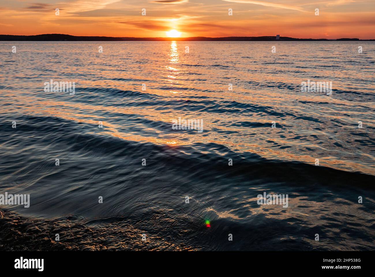 I raggi del sole si riflettono nell'acqua al tramonto Foto Stock