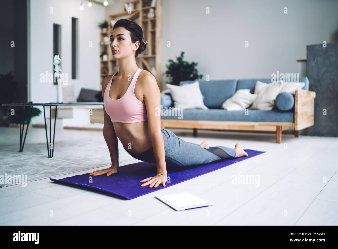 Sportivo giovane e concentrato che pratica lo yoga a casa Foto Stock