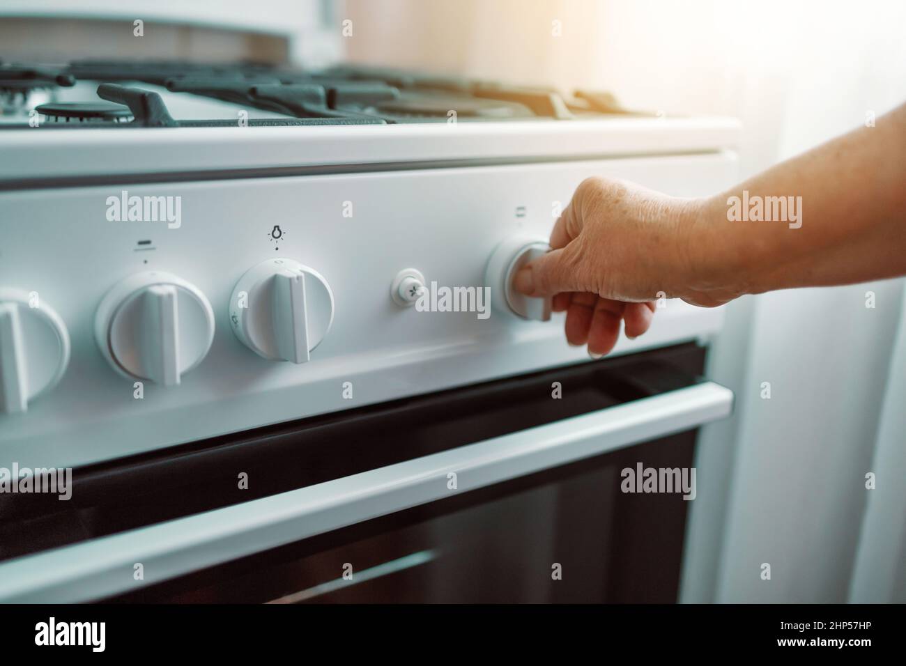 La mano della donna regola la temperatura della stufa a gas nuova Foto Stock