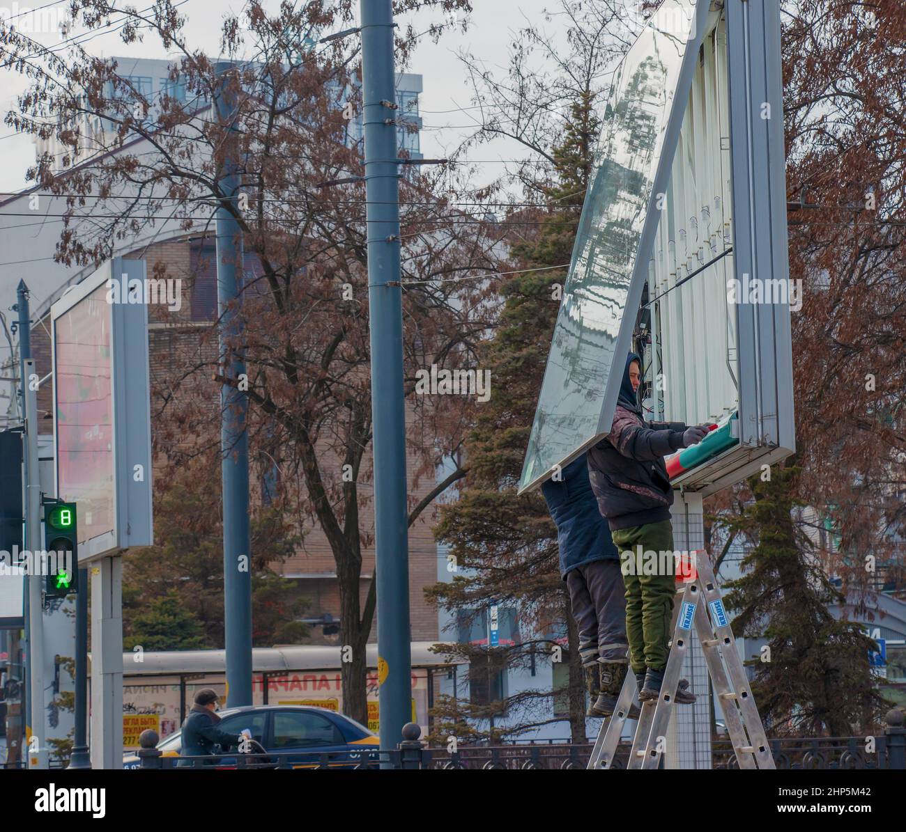 Dnepropetrovsk, Ucraina - 02.09.2022: Installazione di pubblicità all'aperto in città. Gli specialisti salgono le scale fino al tabellone. Lavoro rischioso. Lavoro Foto Stock