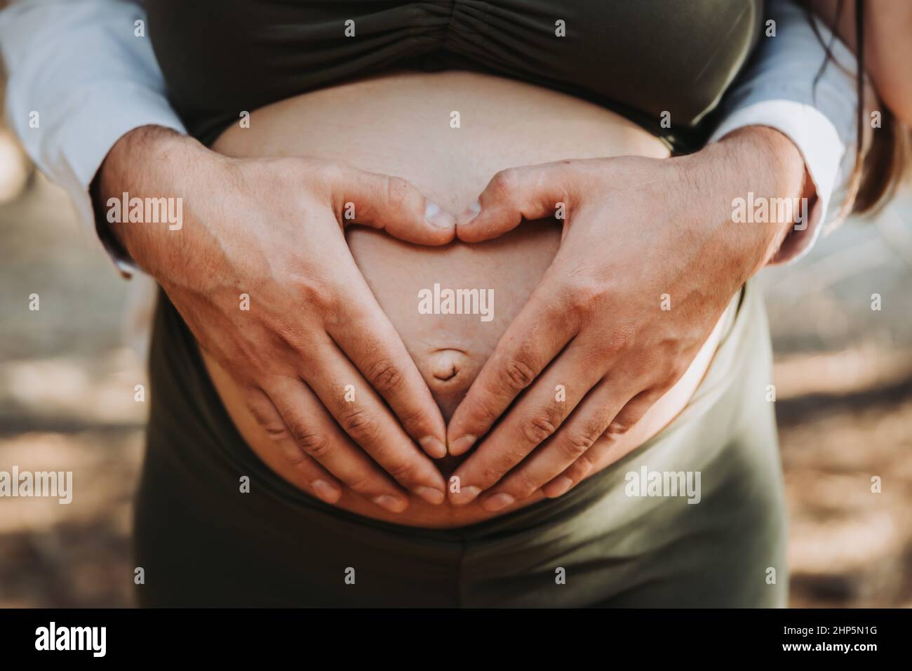Il cuore del Padre forma le mani che toccano il ventre della maternità incinta della madre. Concetto di gravidanza. Parentness Foto Stock