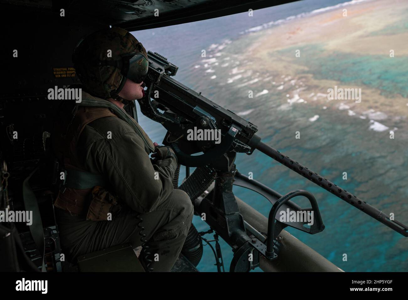 Una Marina degli Stati Uniti con attacco di luce Marina Helicopter Squadron (HMLA) 369 scansiona l'orizzonte in un elicottero UH-1Y Venom durante un evento di addestramento dal vivo-fuoco a sostegno di Jungle Warfare esercizio 22 su IE Shima isola, Giappone, 15 febbraio 2022. JWX 22 è un esercizio di formazione sul campo su larga scala incentrato sull'utilizzo delle capacità integrate di partner congiunti e alleati per rafforzare la consapevolezza, le manovre e gli incendi di tutti i domini in un ambiente marittimo distribuito. (STATI UNITI Foto di Marine Corps di PFC. Justin J. Marty) Foto Stock