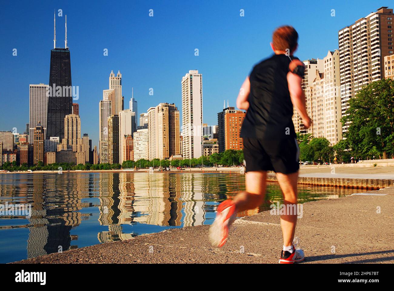 Un giovane uomo corre lungo il lago Michigan Waterfront, con vista completa dello skyline di Chicago Foto Stock