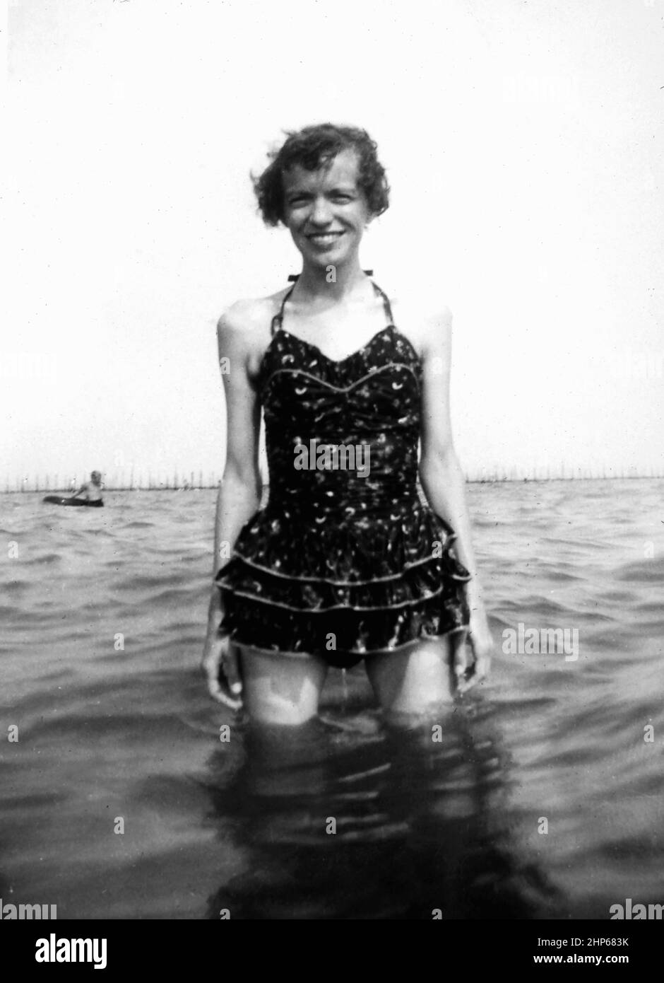 Una donna sorride mentre si gode in piedi in acqua, ca. 1930. Foto Stock