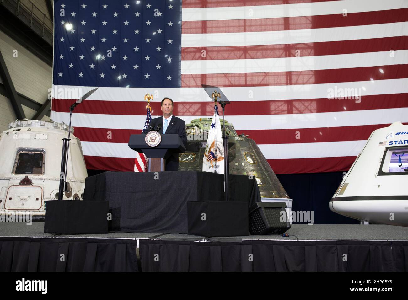 Deliberando amministratore della NASA Robert Lightfoot indirizzi leader dell'agenzia, gli Stati Uniti e il governo della Florida i funzionari e i dipendenti all'interno del complessivo del veicolo la costruzione presso NASA Kennedy Space Center in Florida durante una visita del Vice Presidente Mike Pence. Pence ha ringraziato i dipendenti per far avanzare la leadership americana nello spazio. A ridosso del podio sono, da sinistra, un volato SpaceX Dragon capsula, il veicolo spaziale Orion volato su Esplorazione prova di volo-1 nel 2014, e un mockup del Boeing CST-100 Starliner. Durante la sua visita a Kennedy, il Vice Presidente ha anche visitato diverse strutture evidenziando il pubblico-spiagg Foto Stock