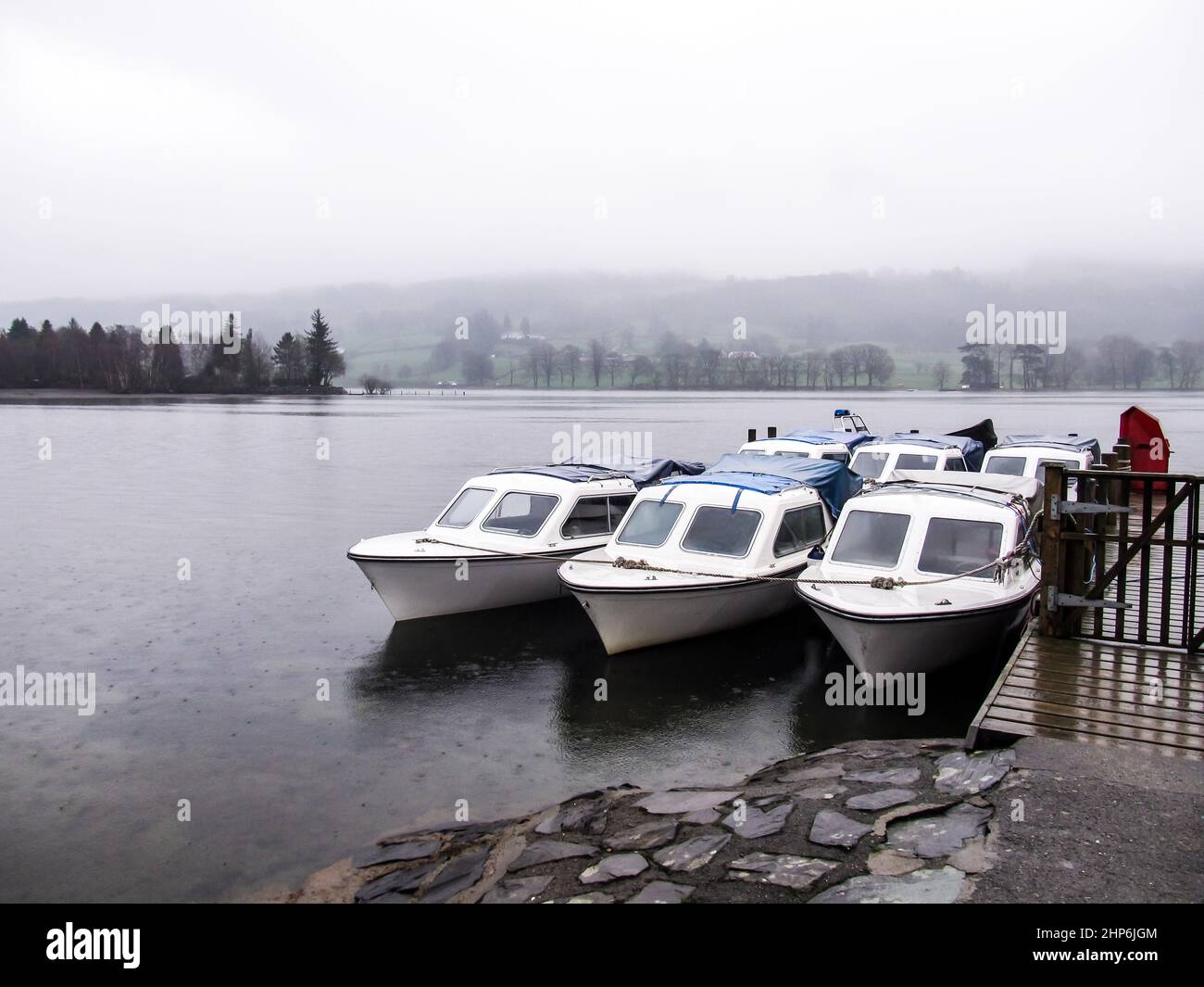 Ormeggiate barche a motore su Coniston Water, Regno Unito, in una giornata di nebbia e pioggia Foto Stock