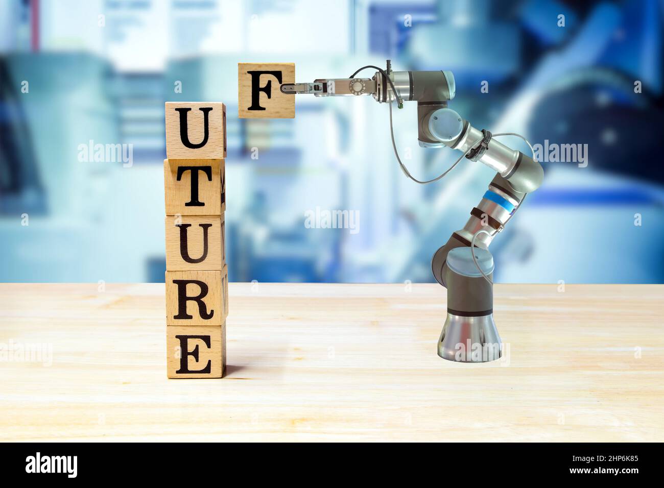 Robot di presa industriale che raccoglie la lettera di legno per messaggio di costruzione su scrivania di legno e macchina colore blu su sfondo sfocato Foto Stock