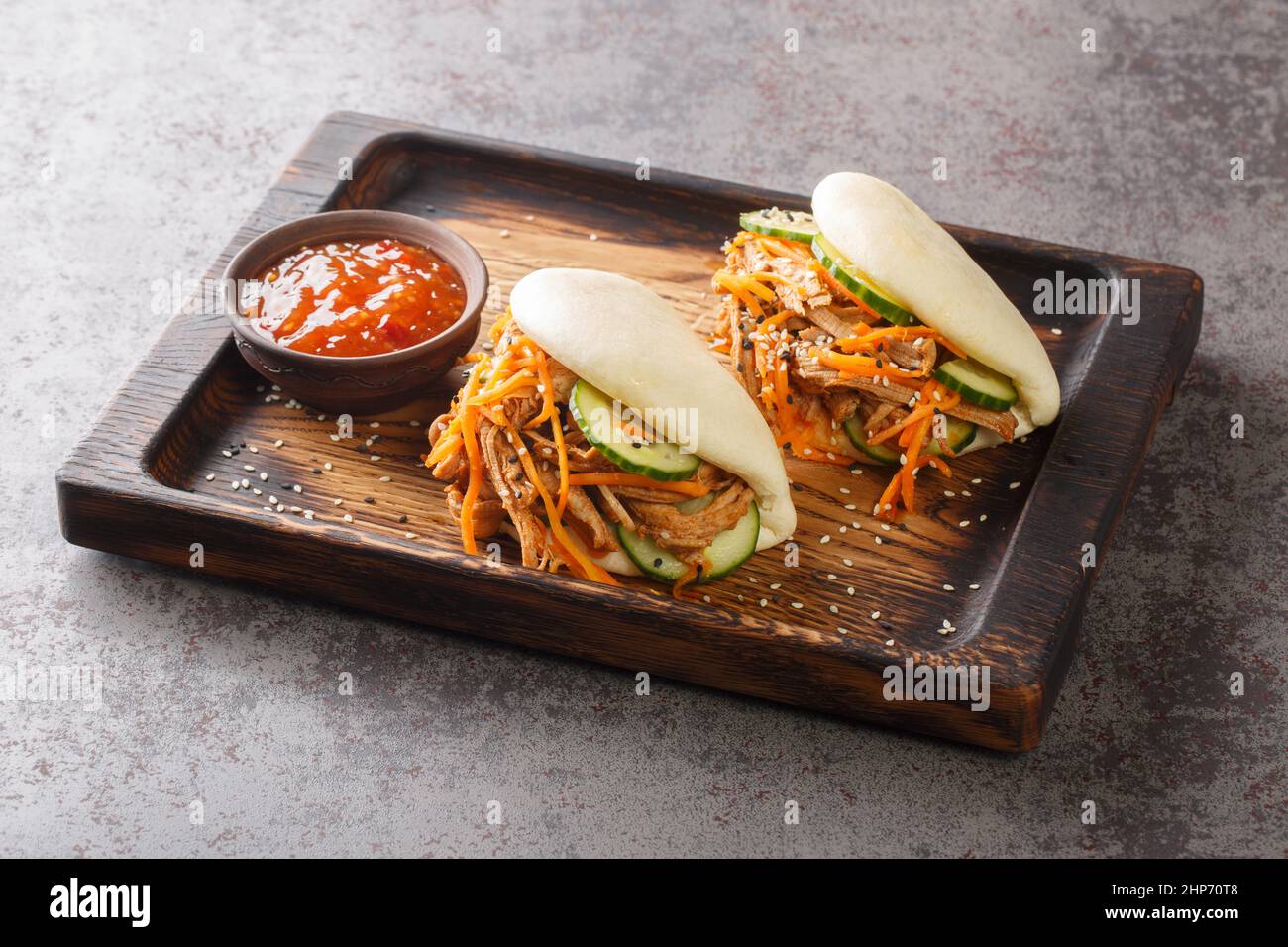 Sandwich bao al vapore con maiale tirato e verdure in primo piano su un vassoio di legno sul tavolo. Orizzontale Foto Stock