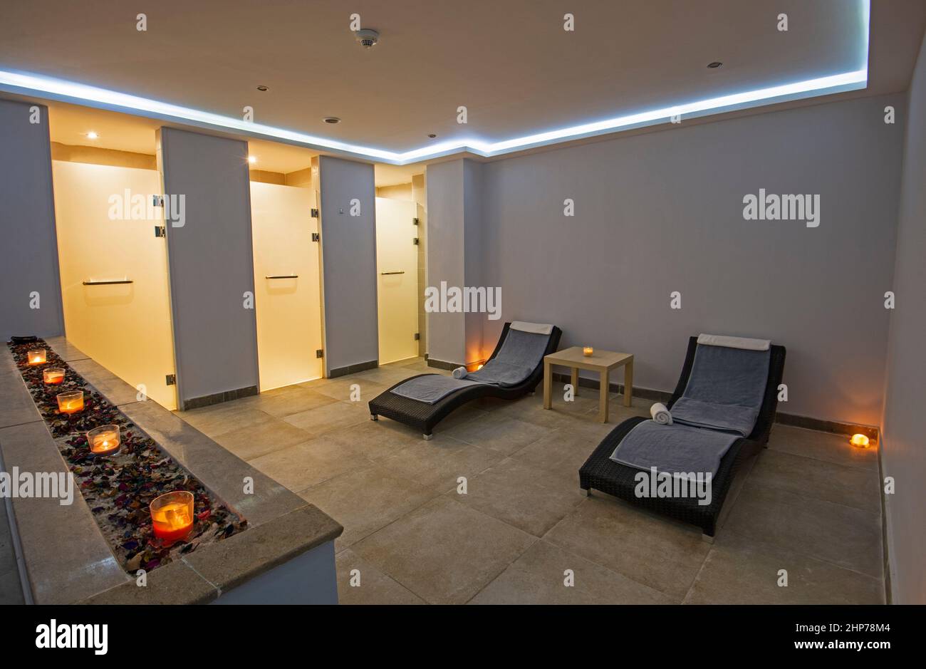Area relax all'interno di un lussuoso centro benessere con letti e asciugamani illuminati da candele Foto Stock