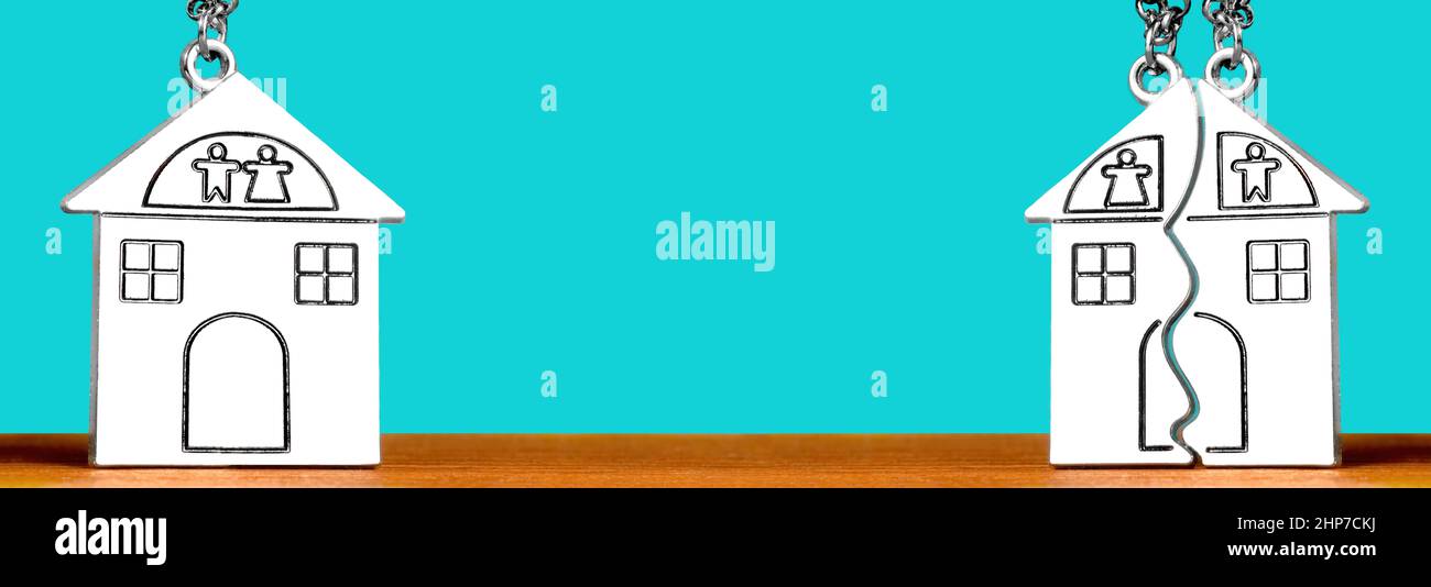 Portachiavi singoli e corrispondenti a forma di casa divisa su un tavolo di legno su sfondo turchese. Regolamento domestico e concetto di divorzio. Foto Stock