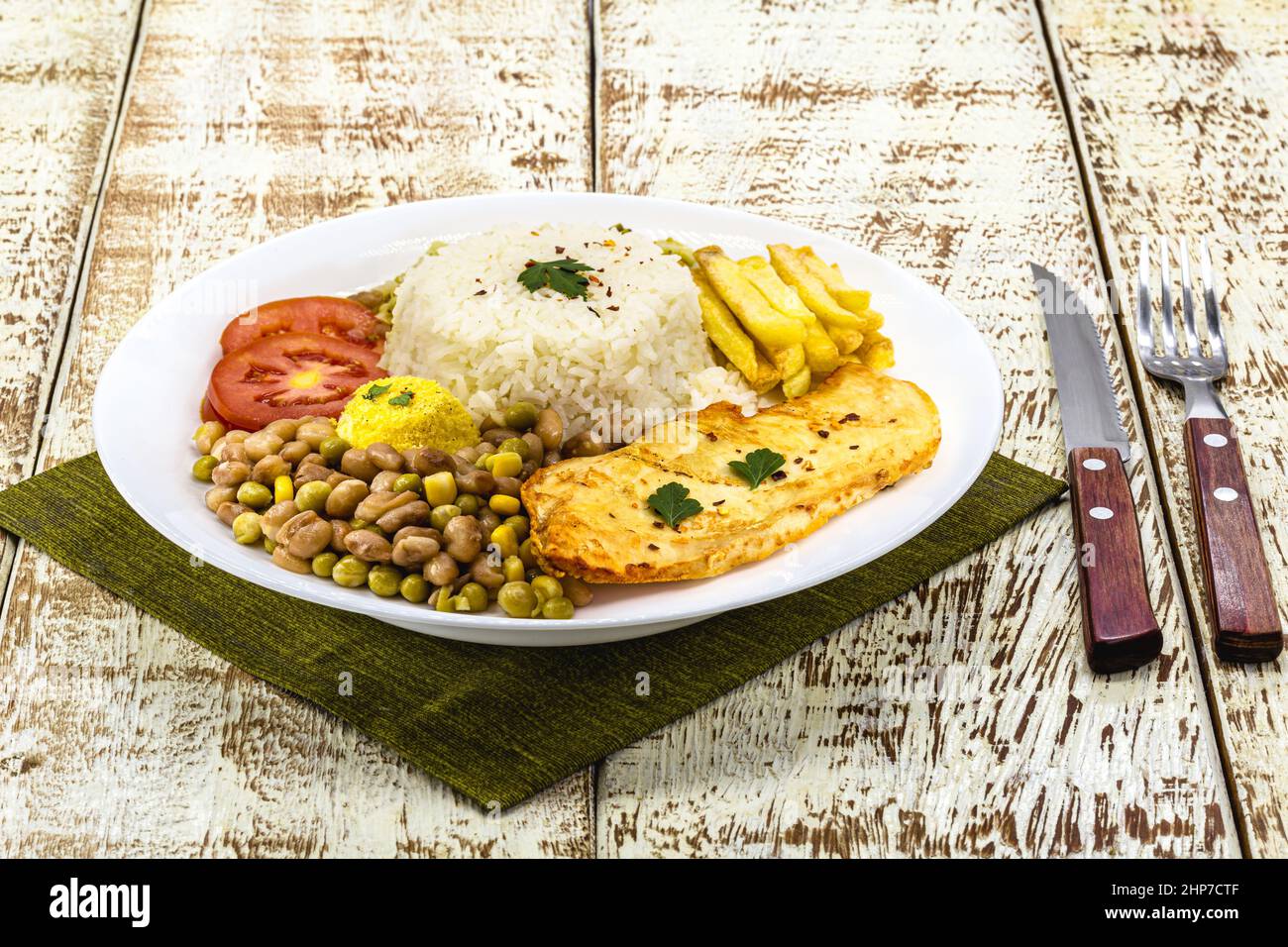riso con fagioli brasiliani, servito con insalata, filetto di pollo fritto e farofa. Servito su un tavolo rustico Foto Stock