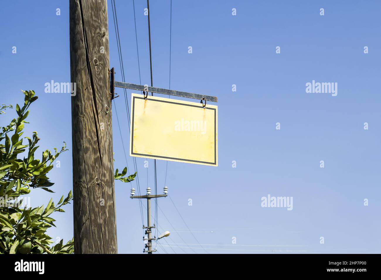 Cartello in metallo bianco appeso su palo di legno con fili elettrici sul cielo blu Foto Stock