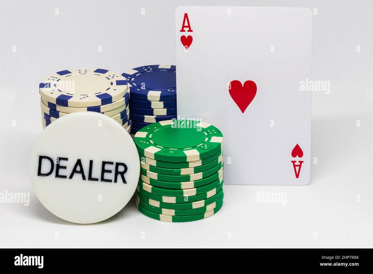 Chip del casinò, carta dell'asso dei cuori e targa con iscrizione del commerciante. Foto Stock