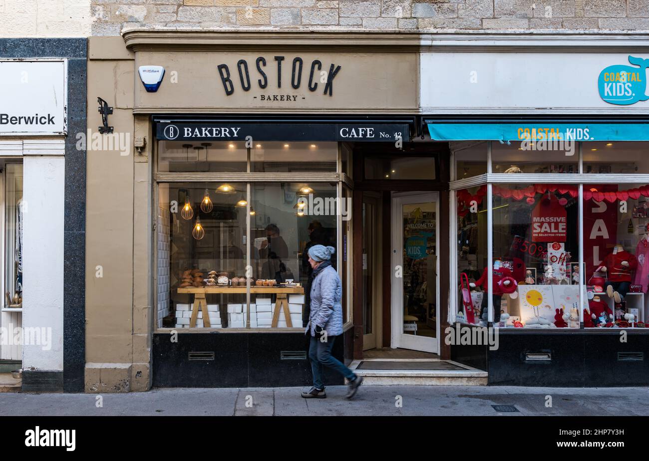 Il negozio di panetteria Bostock si trova davanti alla donna che passa accanto alla pasticceria High Street, North Berwick, Scozia, Regno Unito Foto Stock