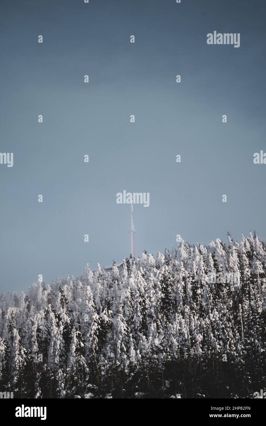 Trasmettitore in cima alla montagna in nuvole con alberi di neve e cielo blu nella Repubblica Ceca Foto Stock