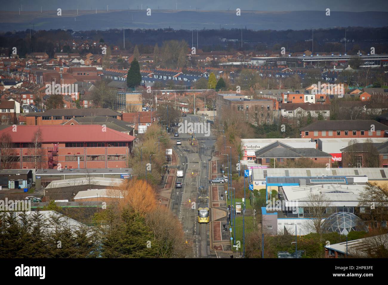 Tram Metrolink sulla South Langworthy Road, Salford, con lo skyline delle case sul tetto oltre Foto Stock
