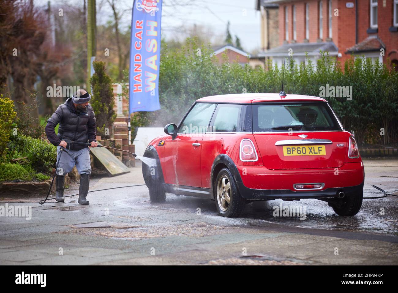 MINI auto ROSSA che viene lavata a getto presso una società di pulizia auto Foto Stock