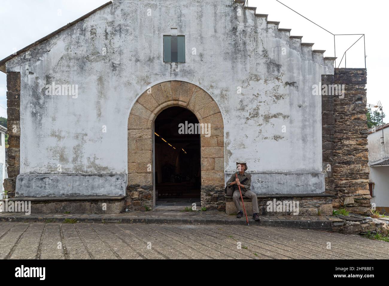 Pellegrino a piedi sul Camino de Santiago, alla porta della chiesa. Via di San Giacomo Foto Stock