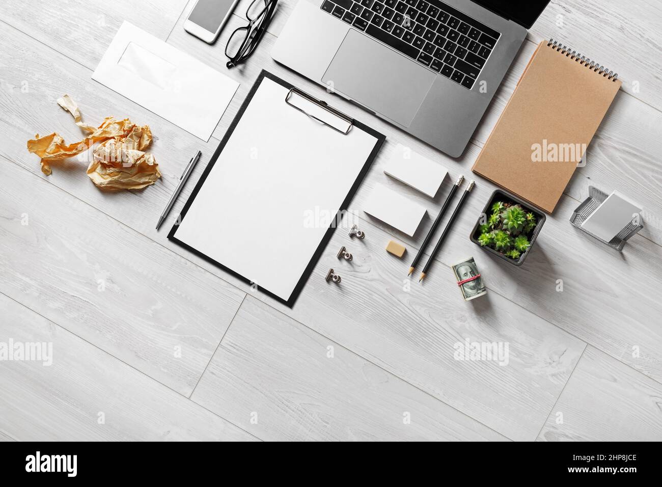 Computer portatile e cancelleria in bianco su sfondo di legno. Concetto aziendale. Disposizione piatta. Foto Stock