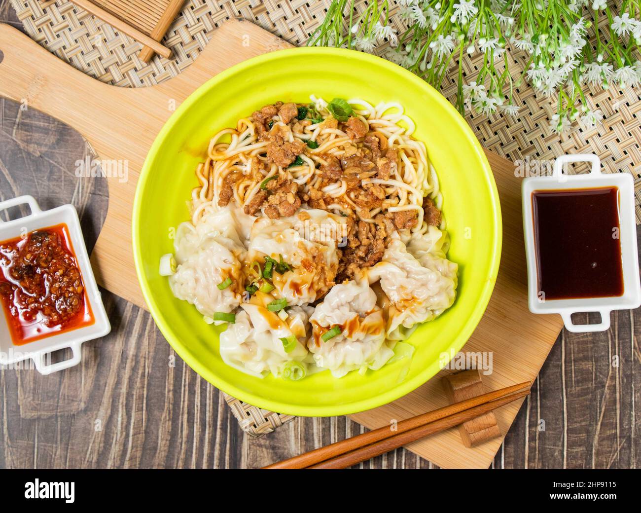 Fresh Pork Wonton Yangchun Noodles con salsa e bastone tritare in una ciotola isolata su legno tagliere vista dall'alto Foto Stock