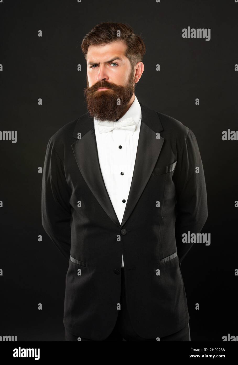 elegante maggiordomo in tuxedo su sfondo nero, abbigliamento formale Foto Stock