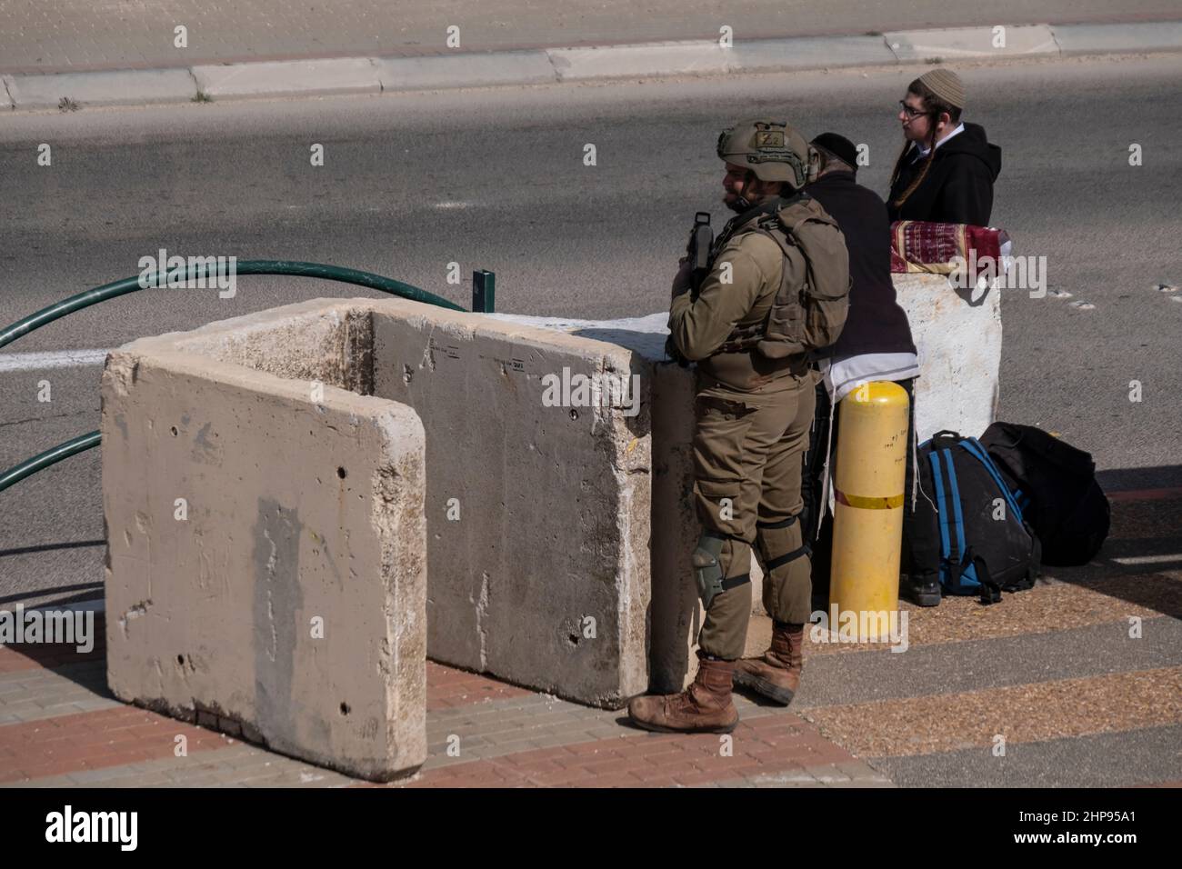 Il soldato israeliano si trova dietro un blocco di cemento in una stazione degli autobus in un incrocio presso lo svincolo di Tabuach il 18 ottobre 2021 in Cisgiordania, Israele. Attualmente, la maggior parte della Cisgiordania è amministrata da Israele anche se il 42% di essa è sotto vari gradi di autonomia da parte dell'autorità palestinese gestita da Fatah. Foto Stock