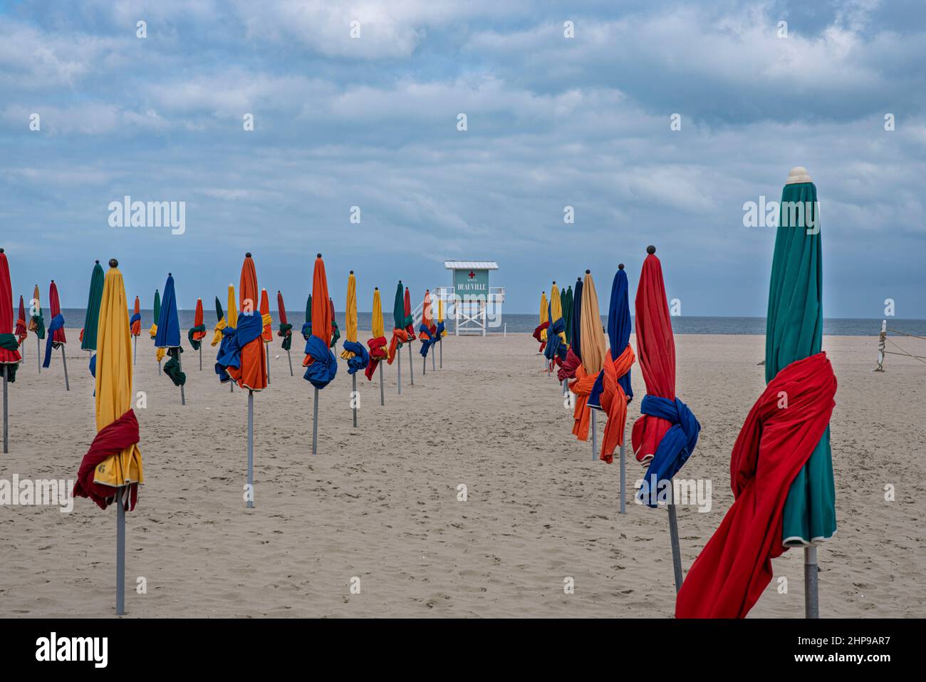 Ombrelloni colorati sulla spiaggia di Deauville in Normandia, Francia con un rifugio bagnino con il nome della città 'Deauville' e 'scue' in inglese o Foto Stock