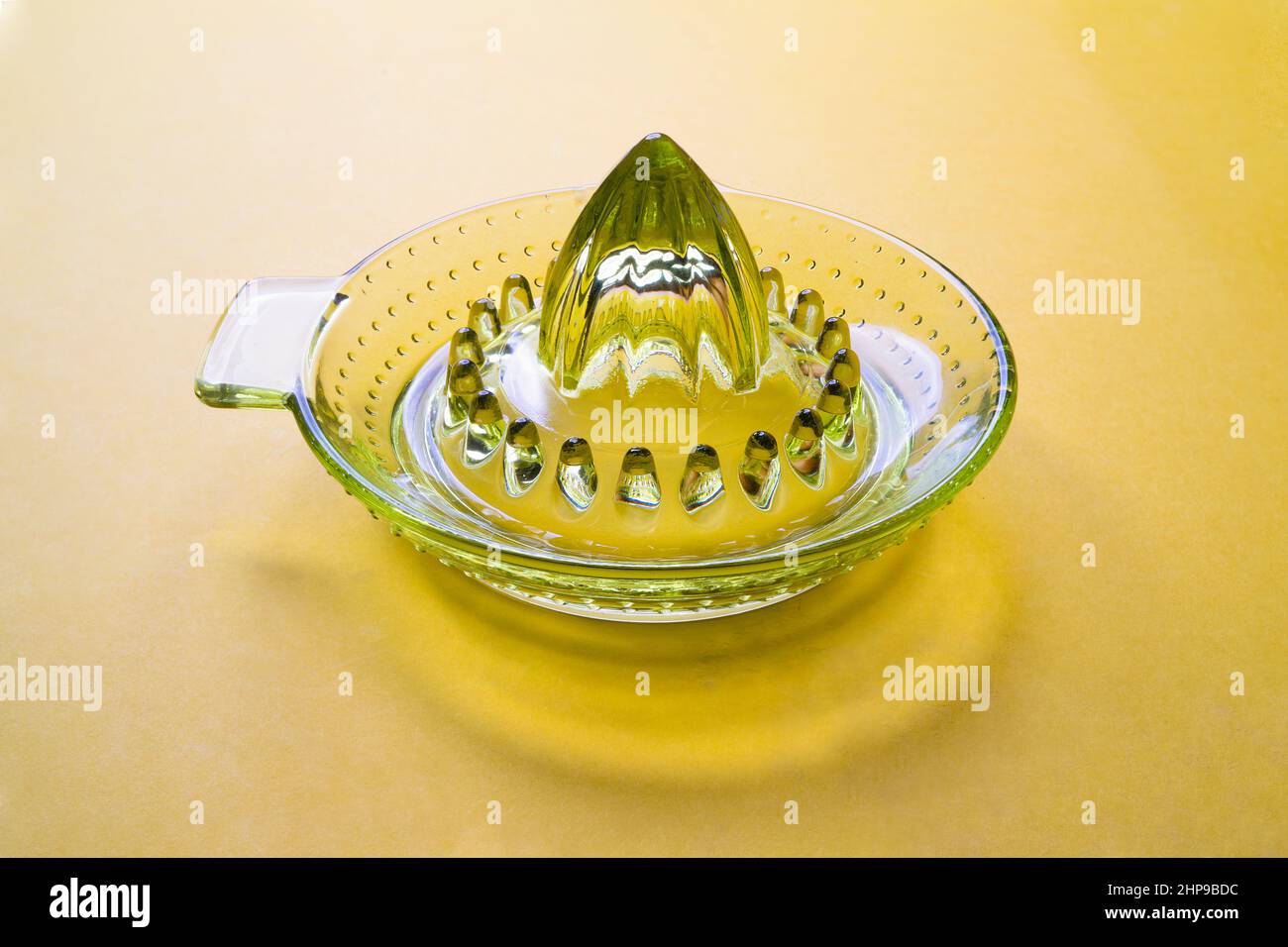 una centrifuga in vetro verde su una superficie colorata Foto Stock