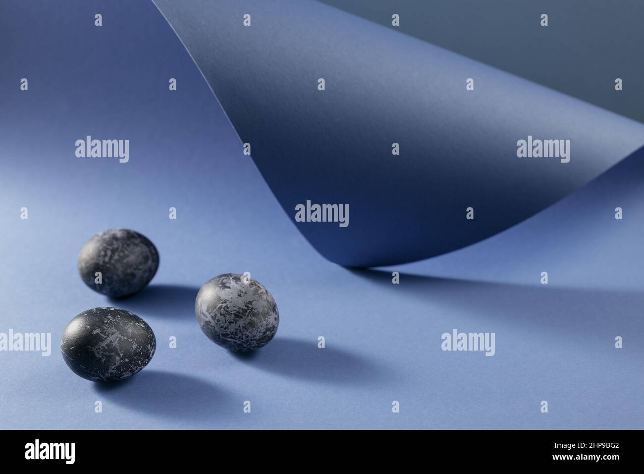 Felice cattolica e ortodossa vacanza di Pasqua sfondo creativo. Pollo pasquale e uova di quaglia dipinte a mano in marmo blu effetto colore su vio Foto Stock