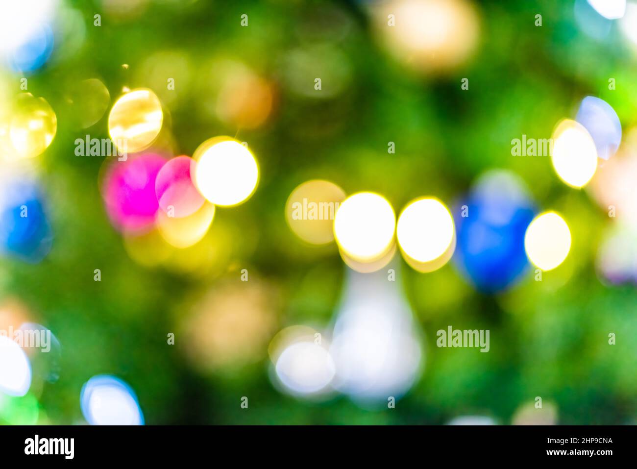 Natale albero bokeh sfondo astratto con giallo, blu e verde ornamenti decorazioni festive luci luminose sfocate cerchi sfocati fuori Foto Stock
