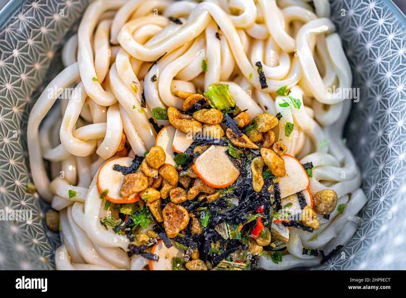Macro closeup piano sopra la vista della noodle giapponese ramen udon zuppa istantanea in ciotola come pasto asiatico con consistenza di condimento secco salsa pacchetto Foto Stock