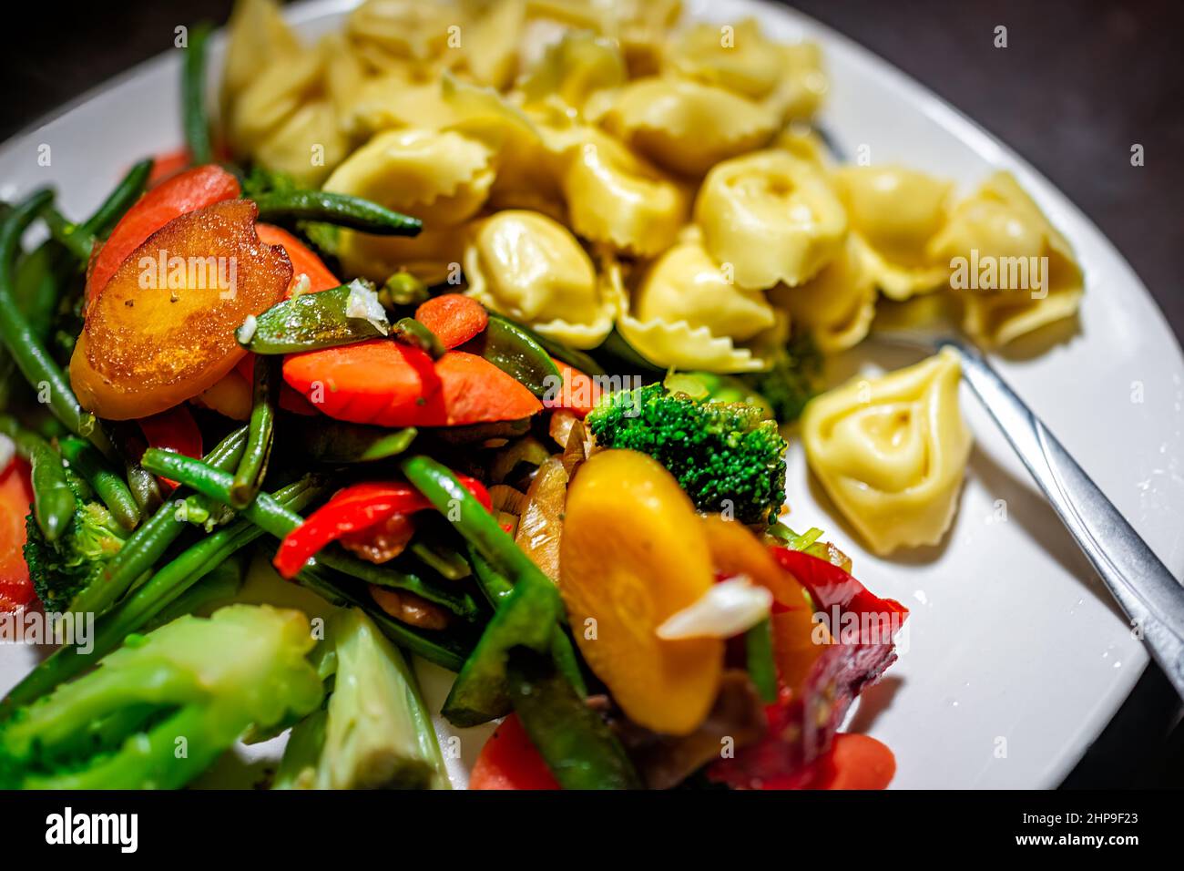 Cena piatto di verdure bianche con mix di carote, broccoli di peperoni rossi e tortellini di salsa ripieni di pasta sul backgrou del tavolo Foto Stock