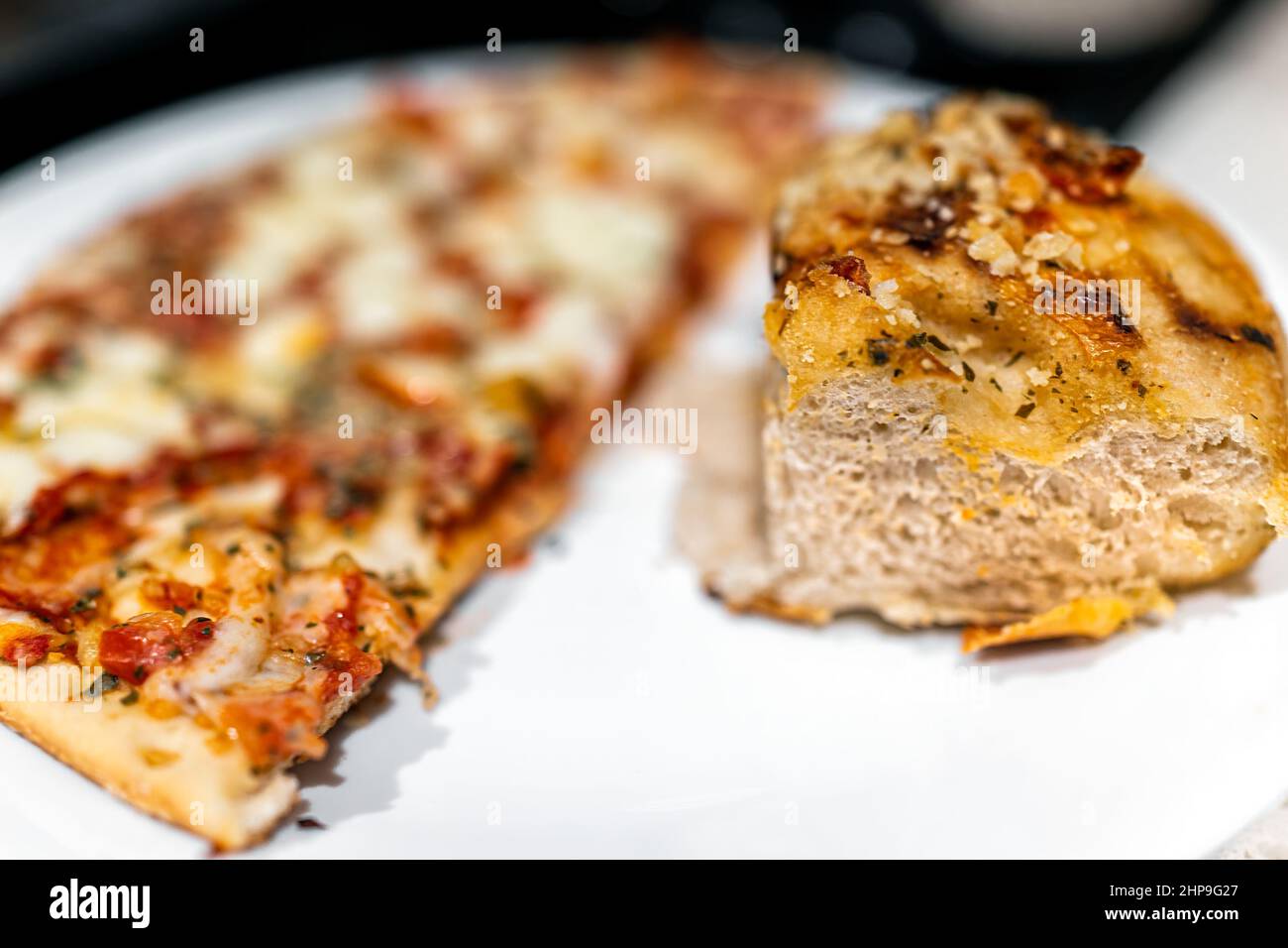 Mezza piccola crosta sottile congelata o pizza fatta in casa con condimenti vegetali e pane di focaccia al pomodoro essiccato al sole su piastra bianca macro closeup Foto Stock