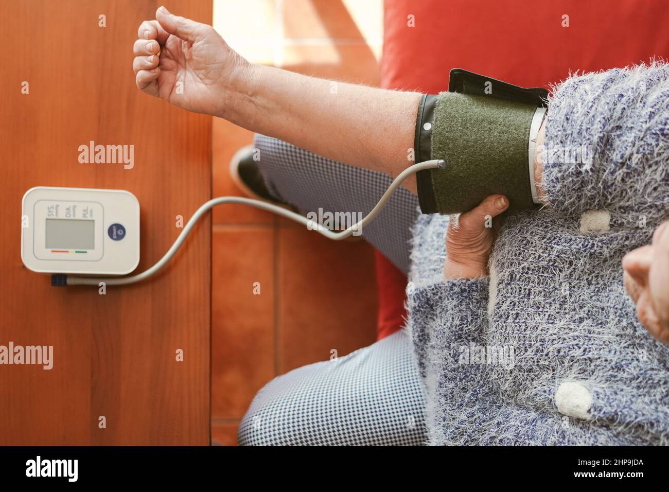 visione zenithal di una donna più anziana che si prepara a prendere la sua pressione sanguigna. Foto Stock