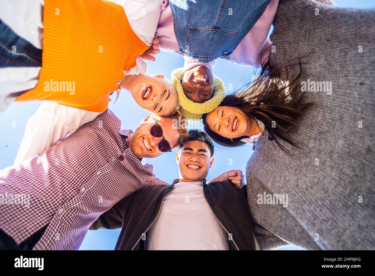 Amici multirazziali che si abbraccia in piedi in cerchio guardando la fotocamera Foto Stock