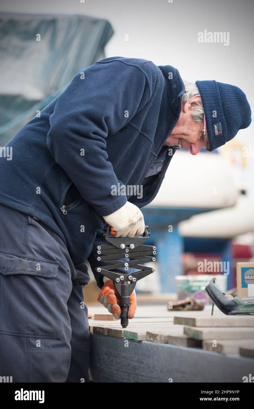 uomo anziano che utilizza una pistola per rivetti a strappo a forbice industriale Foto Stock